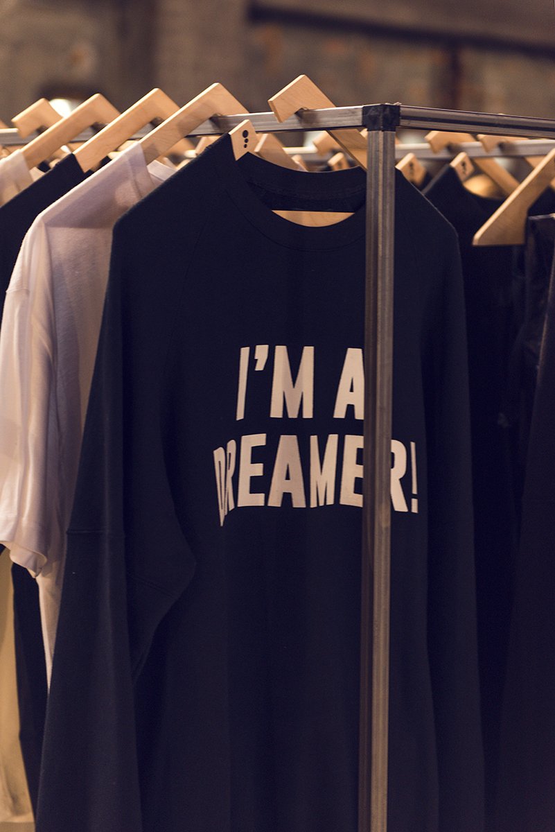 Dark sweatshirt printed with the words “I’M A DREAMER!” on a clothing rail