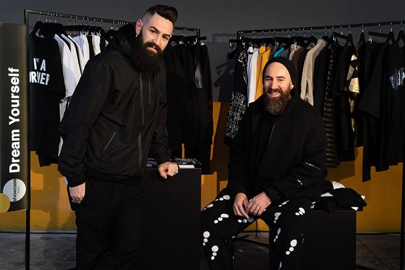 Lorenzo and Emanuele Manta at Altaroma, in front of rails of clothing