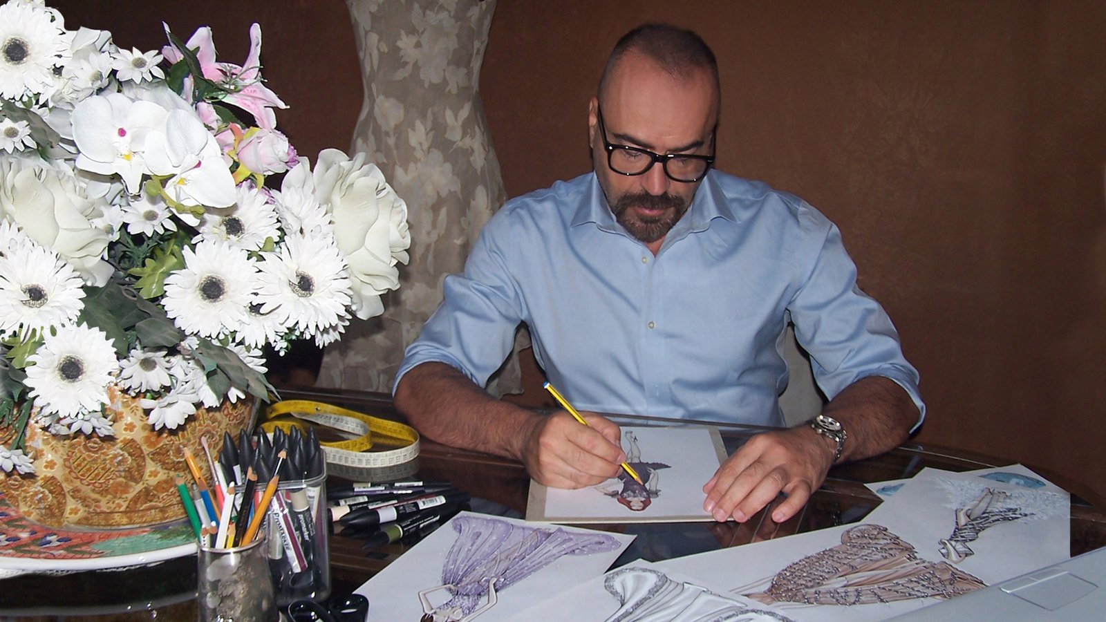 Fabio Menconi drawing a fashion sketch at his desk.
